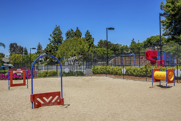 Dog park at Presidio at Rancho Del Oro Apartments featuring grassy play areas and agility equipment