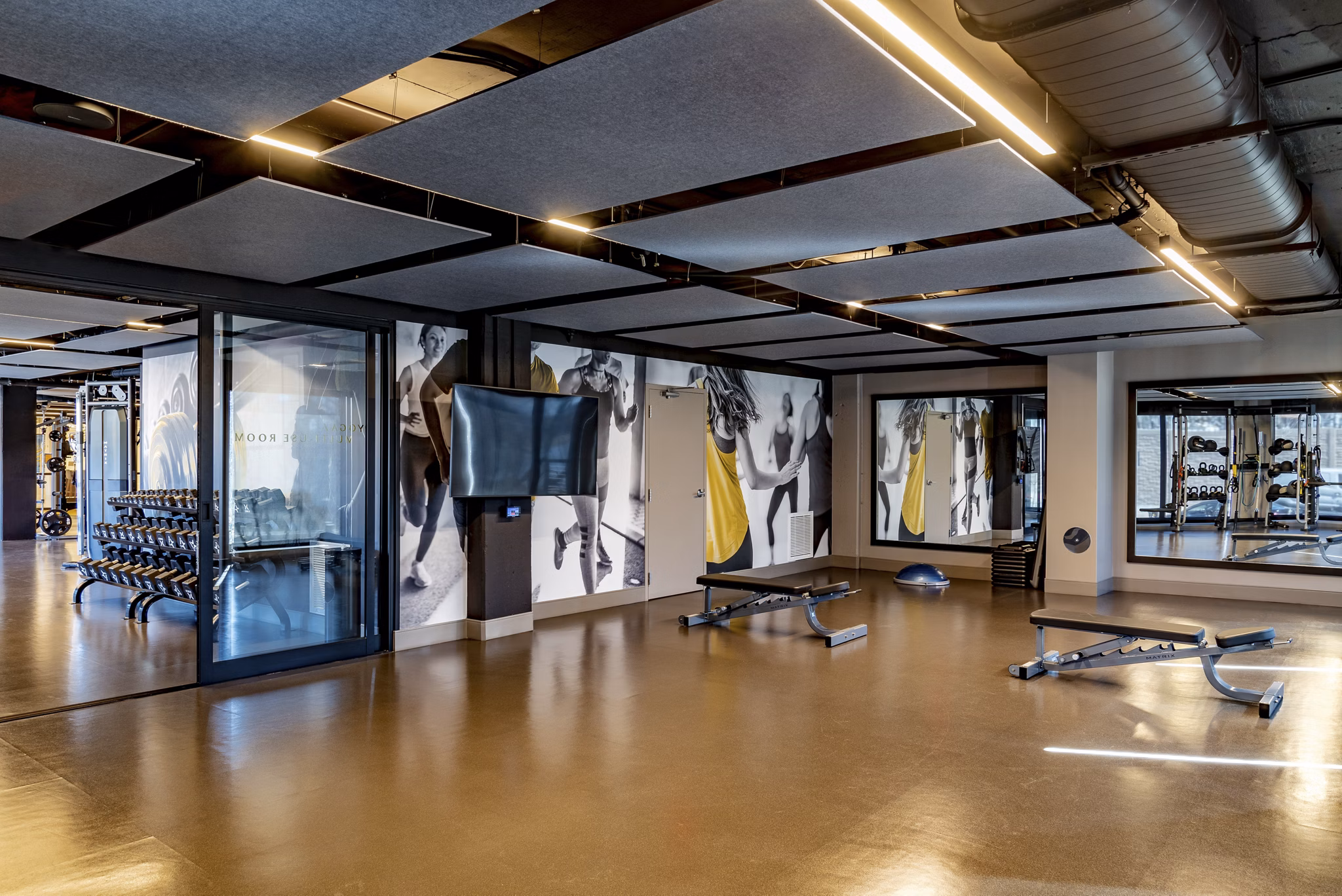 Modern gym featuring exercise equipment, benches, and weights in luxury apartments