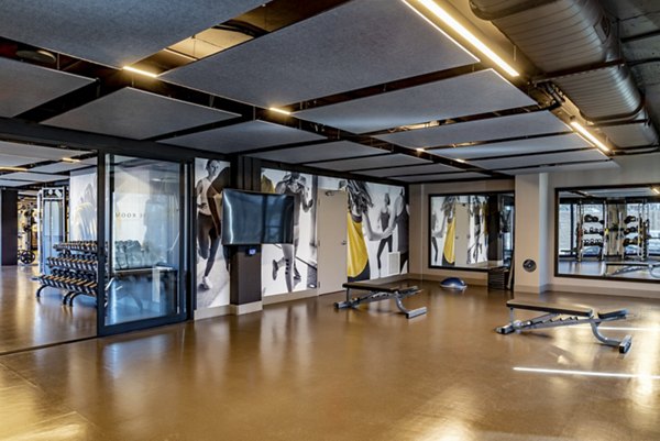 Modern gym featuring exercise equipment, benches, and weights in luxury apartments