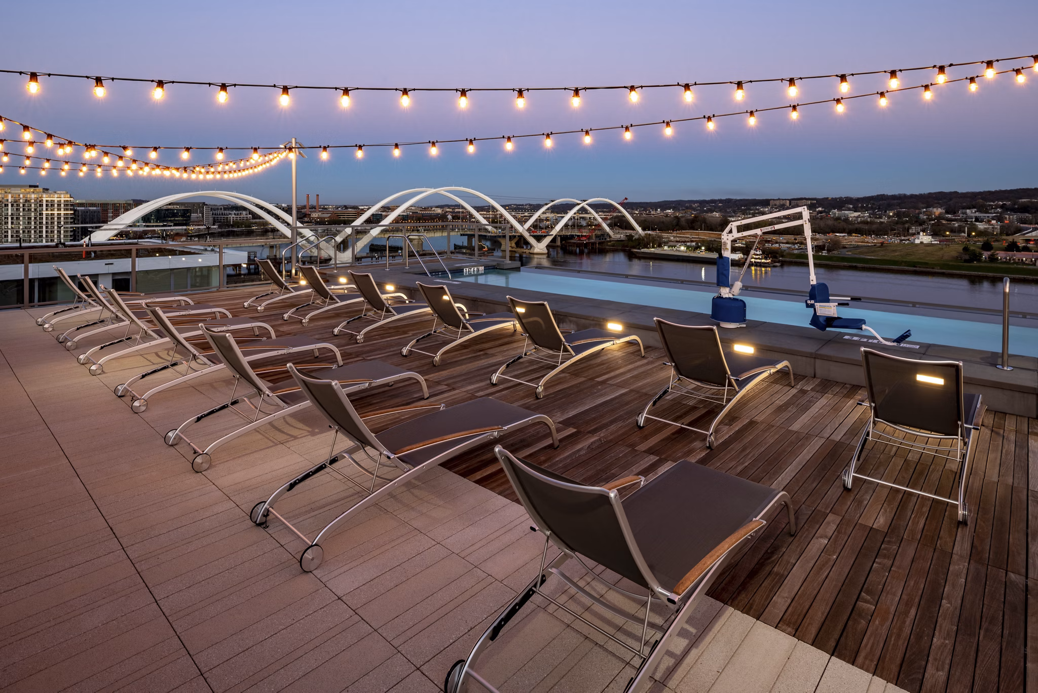 Rooftop pool with lounge chairs and string lights at luxury apartments