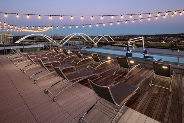 Rooftop pool with lounge chairs and string lights at luxury apartments