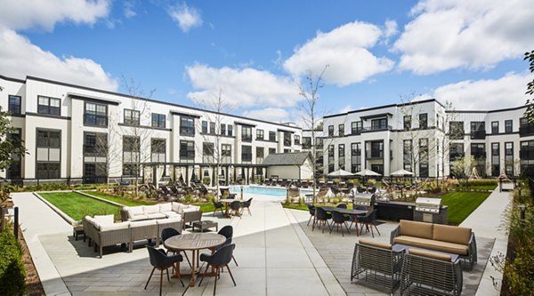 Relaxing poolside ambiance at The Atworth at Mellody Farms Apartments with lush landscaping and cozy loungers, perfect for leisure