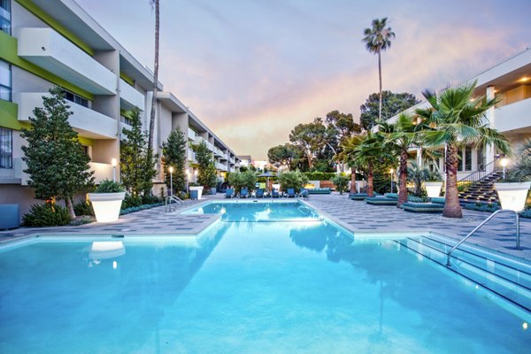 Luxurious pool with lounge chairs and palm trees at The Chadwick Apartments