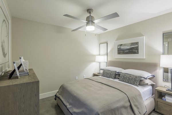 Stylish bedroom featuring minimalist decor and large windows at Eighteen25 Downtown Apartments