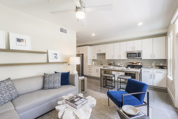 Cozy living room with modern decor and large windows in Eighteen25 Downtown Apartments, offering comfort and style in urban living spaces