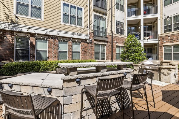 Outdoor grill area with modern seating and landscaping at Whetstone Apartments, perfect for social gatherings and dining alfresco