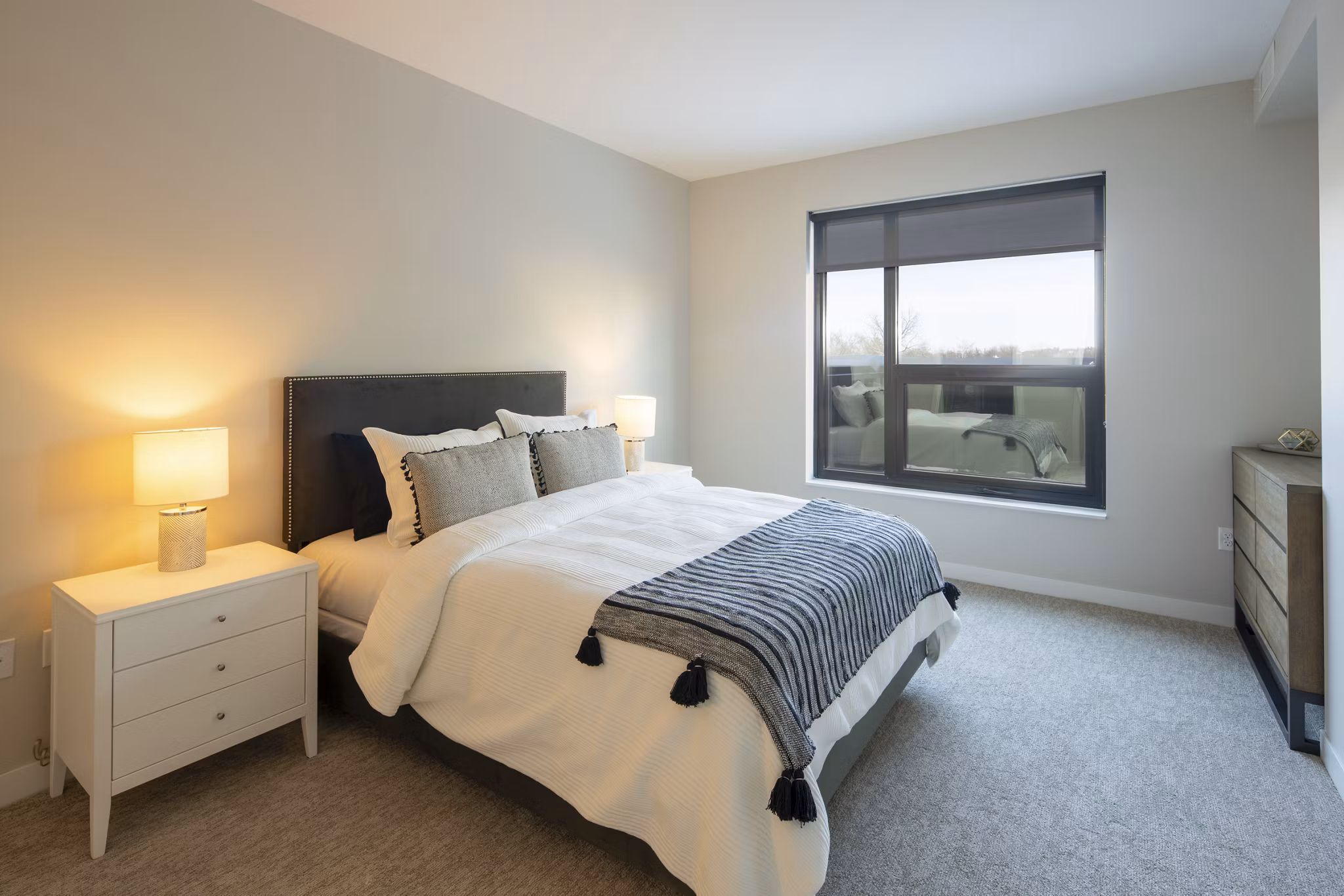 Cozy bedroom with stylish decor and large windows at The Berkman Apartments, a luxury residence in a prime location