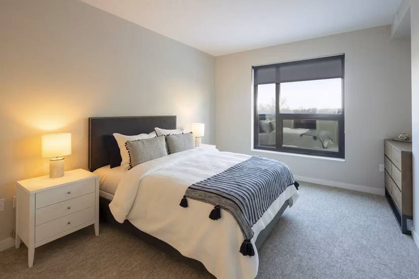 Cozy bedroom with stylish decor and large windows at The Berkman Apartments, a luxury residence in a prime location