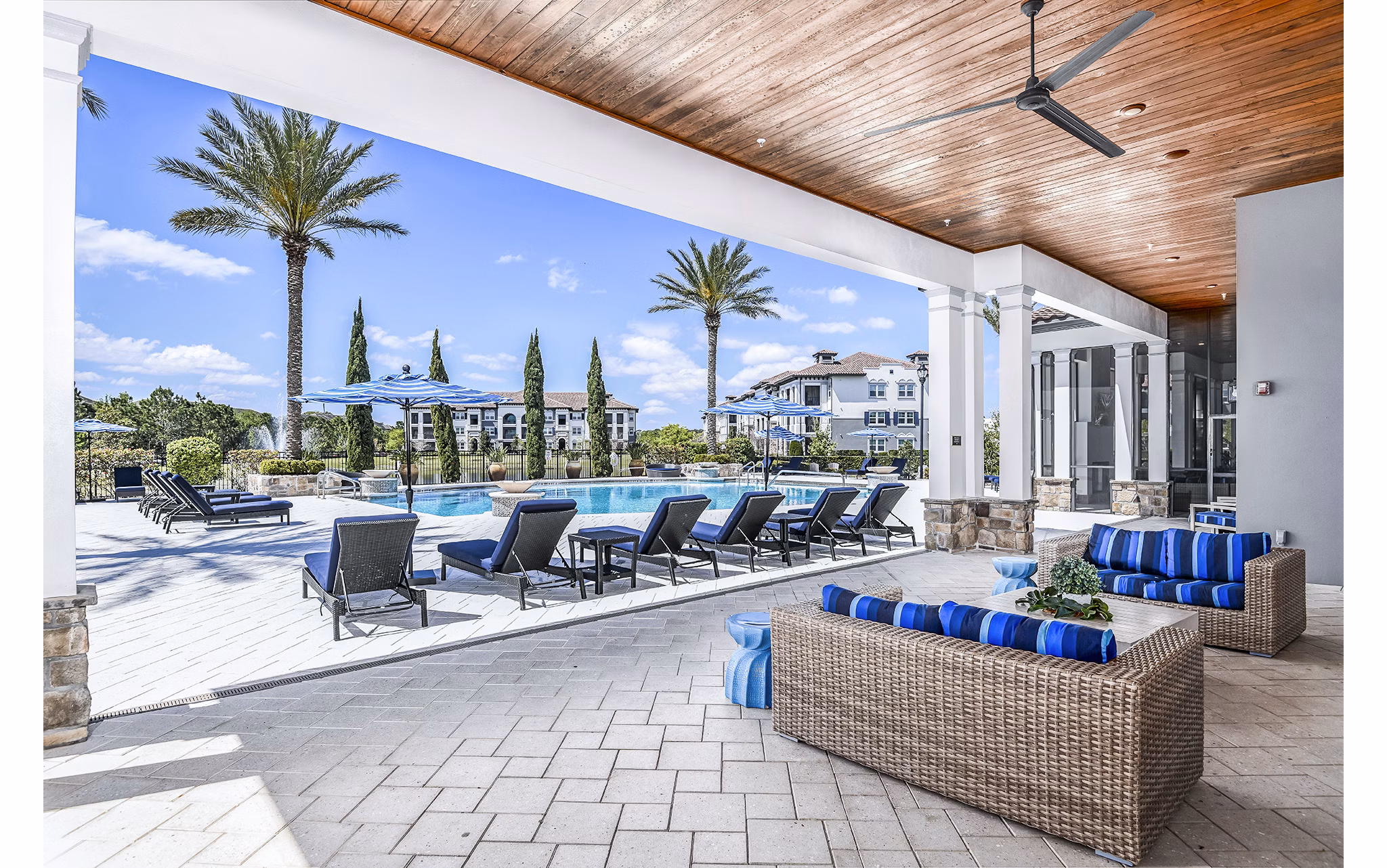 Venetian Isle Apartments: Relaxing pool patio with lounge chairs and palm trees, perfect for outdoor leisure and luxury living