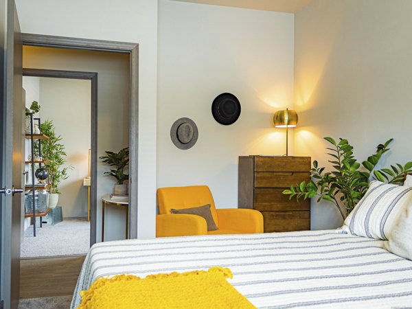 Cozy bedroom with modern decor at Broadway190 Apartments, featuring comfortable bedding and ample natural light