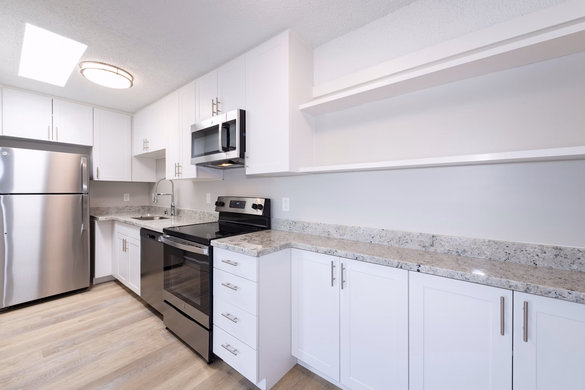 Modern kitchen with granite countertops and stainless steel appliances at Oak & Iron luxury apartments