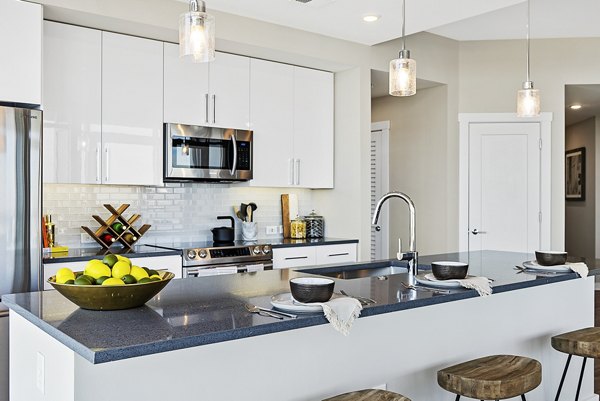 Modern kitchen with stainless steel appliances and granite countertops at Element SouthPark Apartments