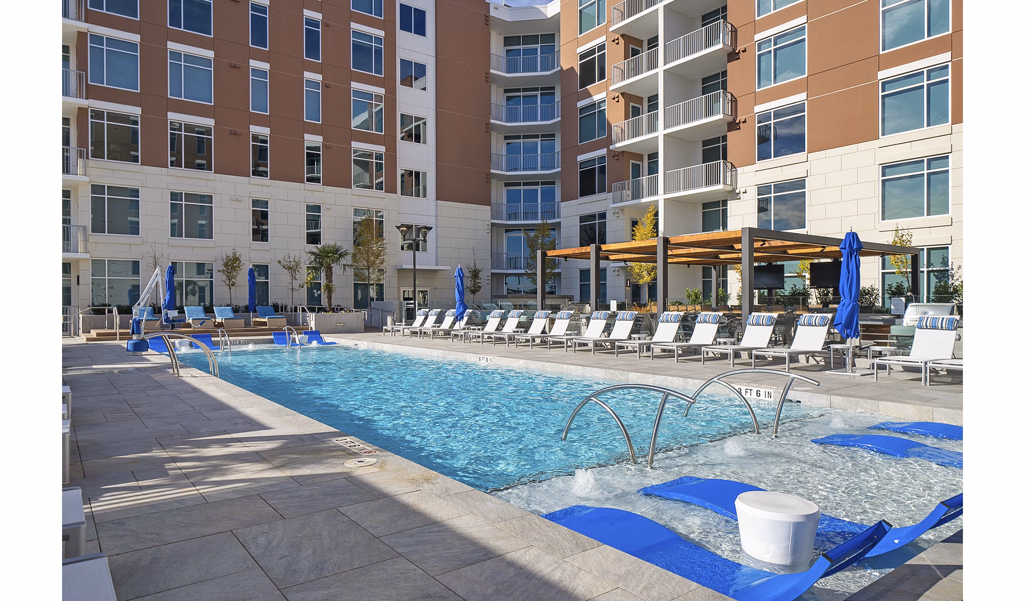 Luxurious outdoor pool at Element SouthPark Apartments featuring elegant lounge chairs and lush landscaping