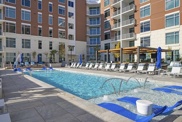 Luxurious outdoor pool at Element SouthPark Apartments featuring elegant lounge chairs and lush landscaping