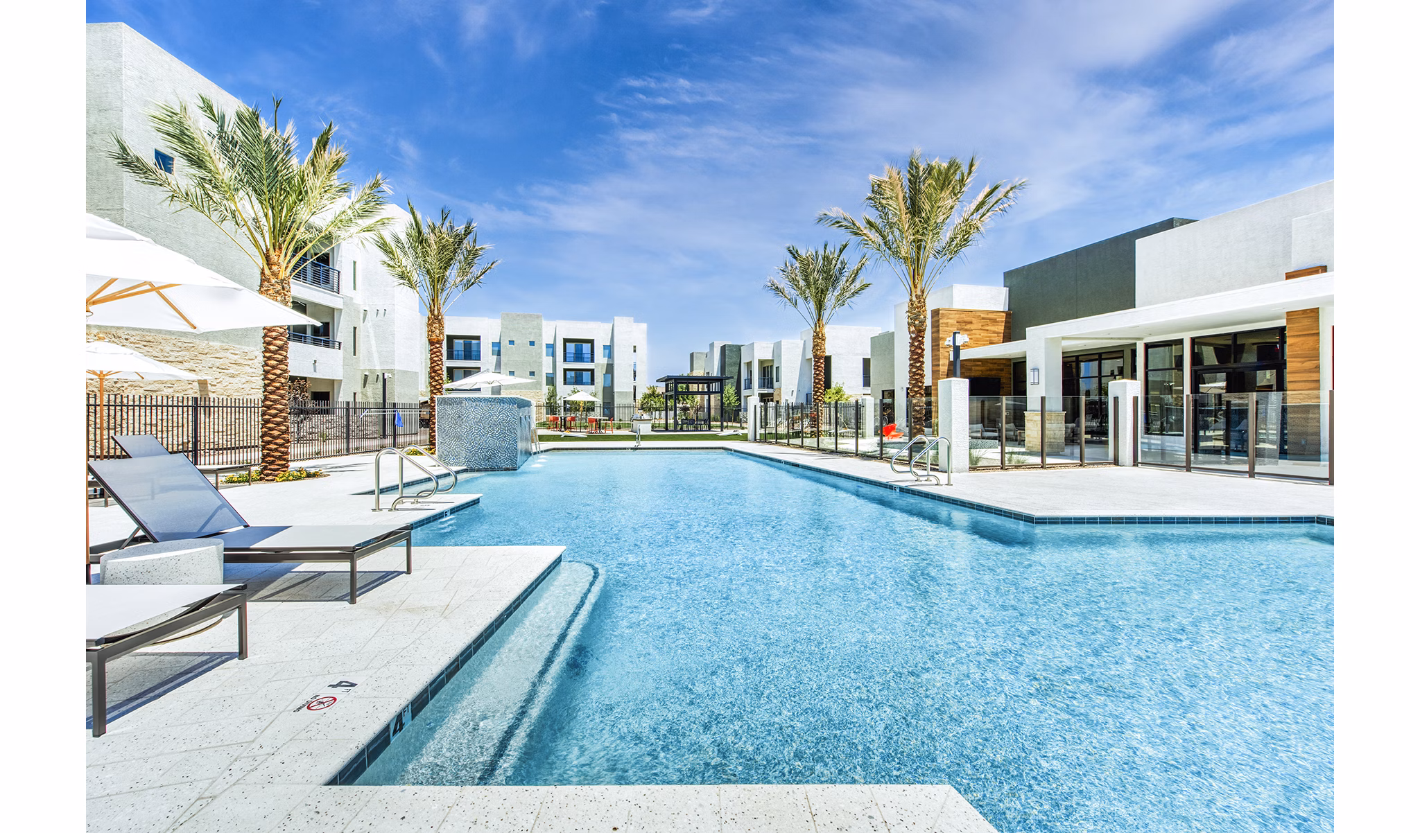 Pool surrounded by palm trees at Amiya Apartments, a luxurious setting for relaxation and leisure