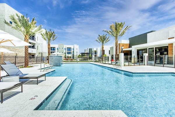 Pool surrounded by palm trees at Amiya Apartments, a luxurious setting for relaxation and leisure