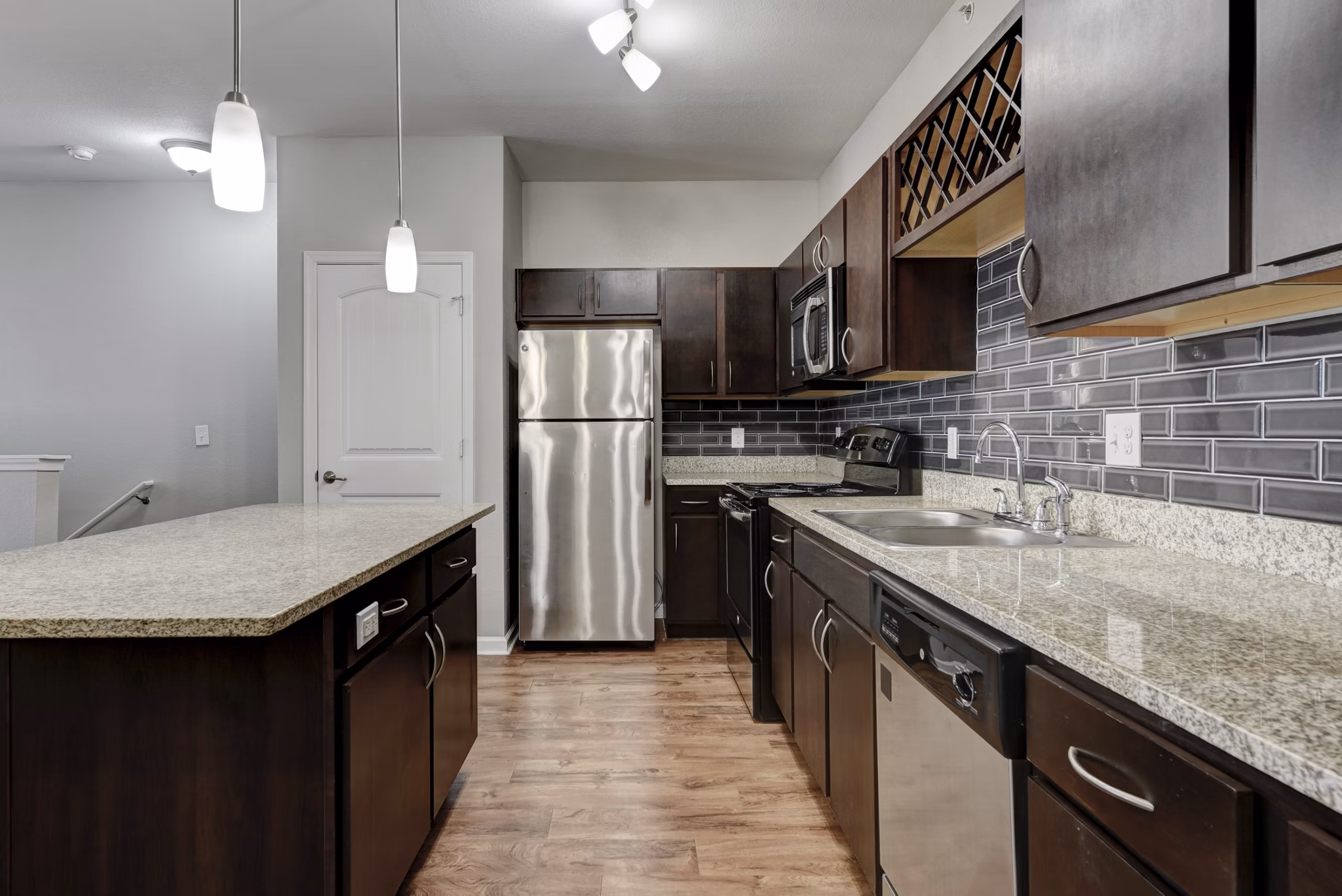 Modern kitchen with stainless steel appliances and granite countertops in Sage Apartments