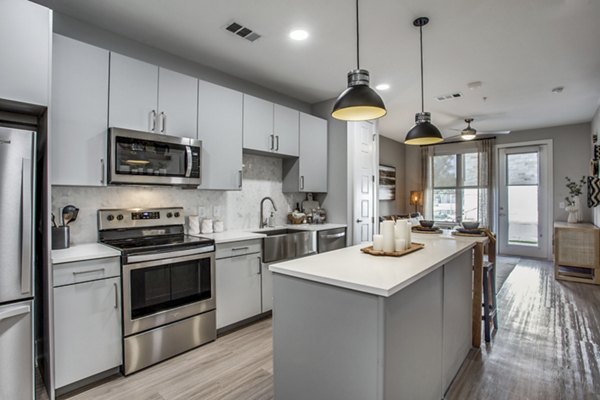 Modern kitchen featuring granite countertops and stainless steel appliances in Trailhead Apartments, luxury living near nature trails