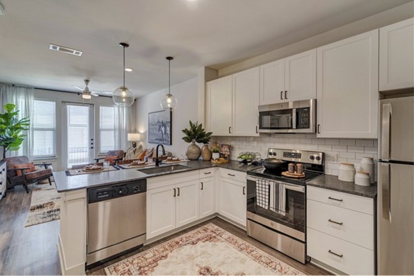 Modern kitchen with stainless steel appliances and quartz countertops at Album Keller Ranch Apartments