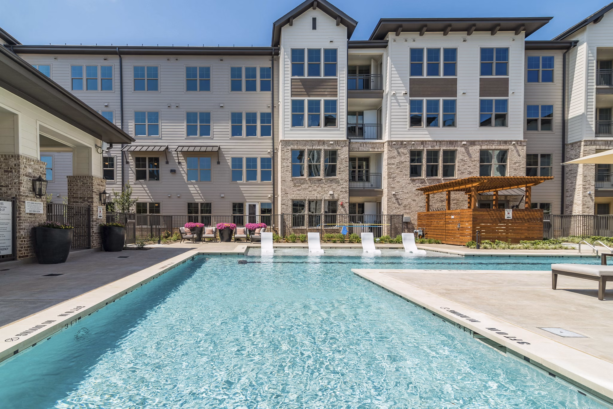 Resort-style pool area with lounge chairs and landscaping at Album Keller Ranch Apartments