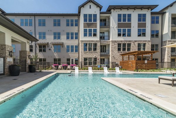 Resort-style pool area with lounge chairs and landscaping at Album Keller Ranch Apartments