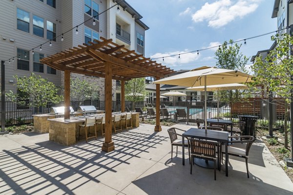 Outdoor grill area at Album Keller Ranch Apartments with modern stainless steel BBQ facilities and seating, perfect for social gatherings
