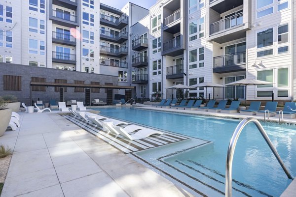 Outdoor swimming pool area with lounge chairs at Alder Apartments luxury community