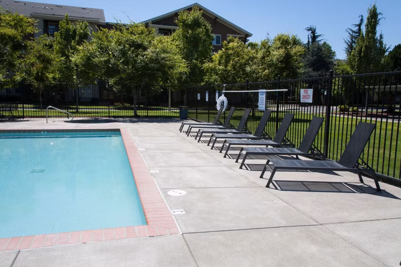 A serene pool area with surrounding lounge chairs at Willamette Gardens Apartments, perfect for relaxation and unwinding in a luxury setting