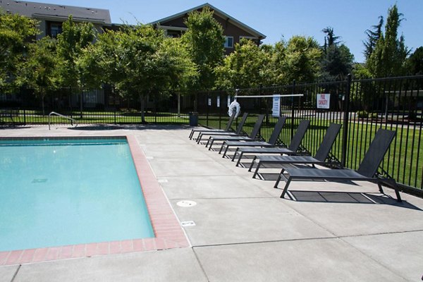 A serene pool area with surrounding lounge chairs at Willamette Gardens Apartments, perfect for relaxation and unwinding in a luxury setting