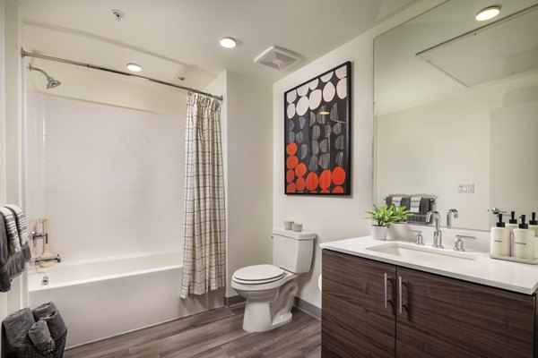 Luxurious bathroom featuring sleek fixtures and large mirrors at Rise Hollywood Apartments