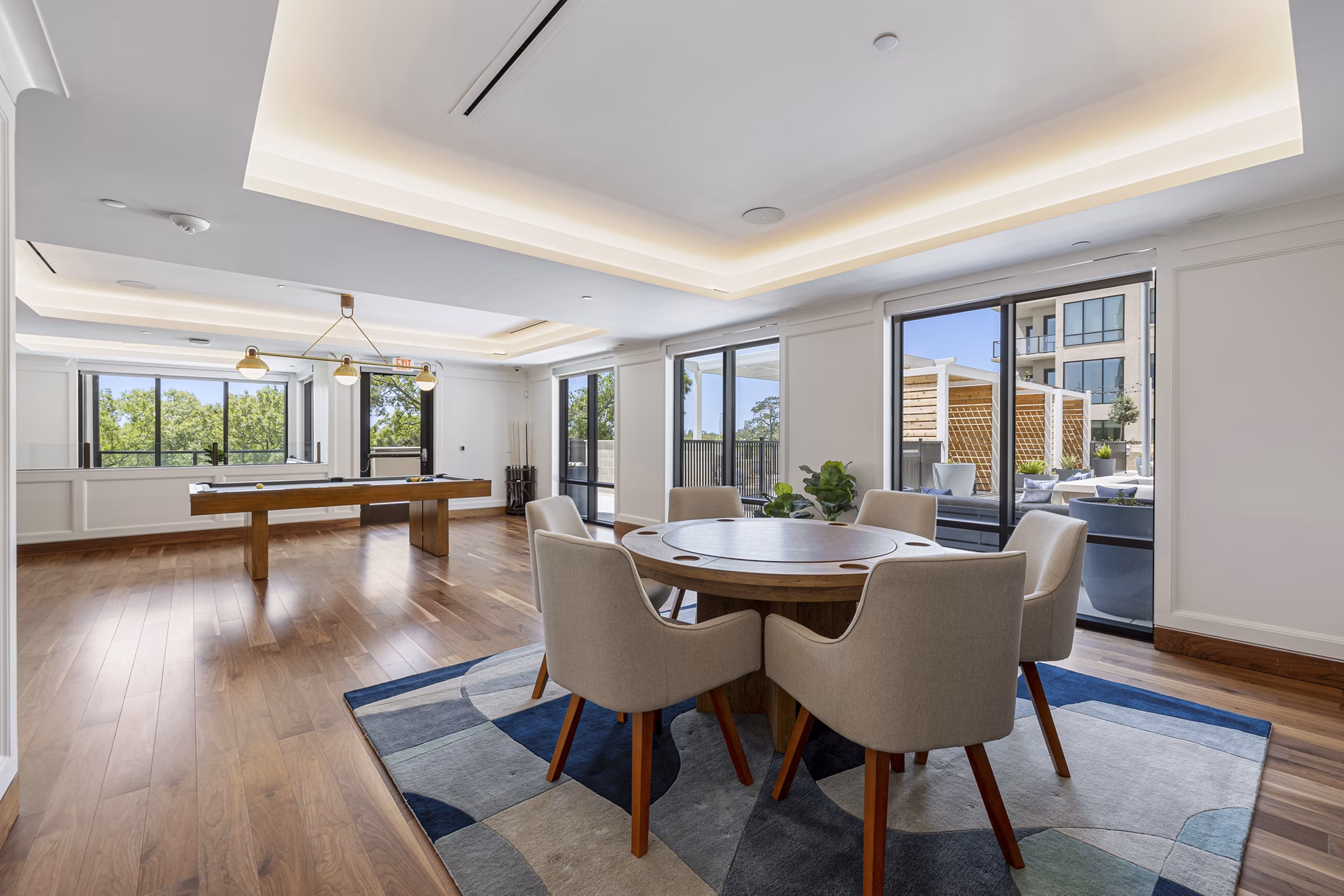 Bright modern dining area with a pool table and large windows in luxury apartments