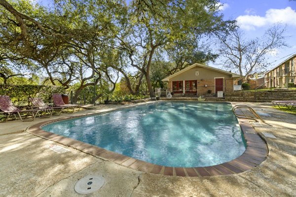 Resort-style pool at Treehouse Apartments with lush landscaping and relaxation spaces