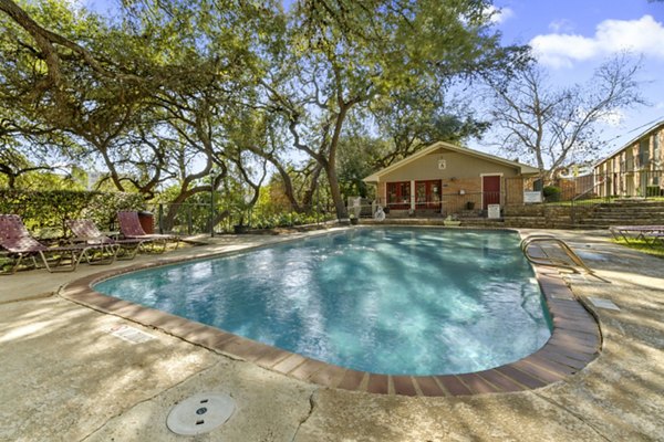 Resort-style pool at Treehouse Apartments with lush landscaping and relaxation spaces