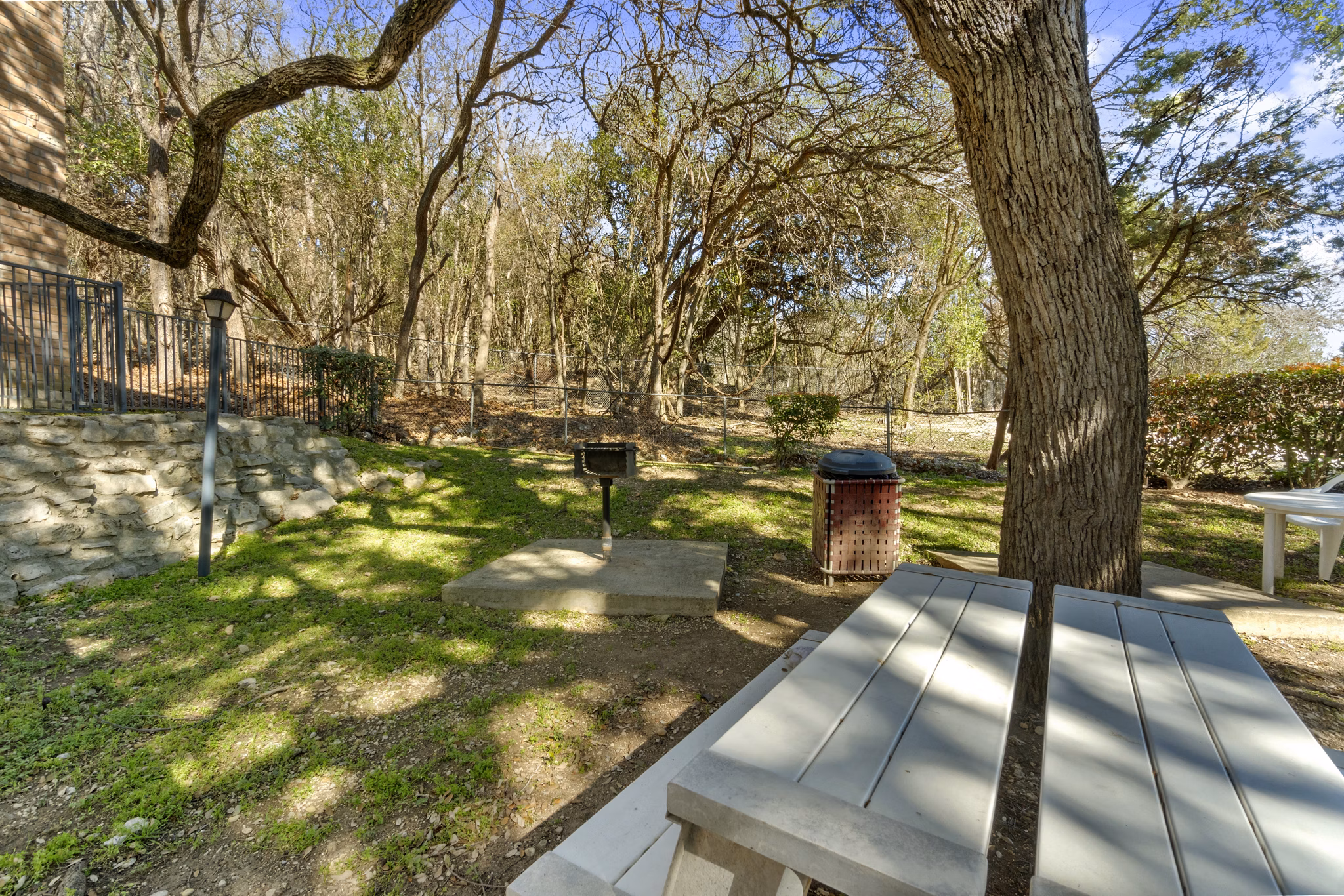 Outdoor grill area surrounded by lush landscaping at Treehouse Apartments, ideal for social gatherings and alfresco dining