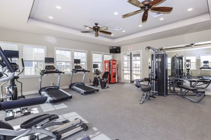 Modern fitness center equipped with weights and machines at Roots at Waco Apartments