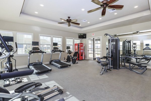 Modern fitness center equipped with weights and machines at Roots at Waco Apartments