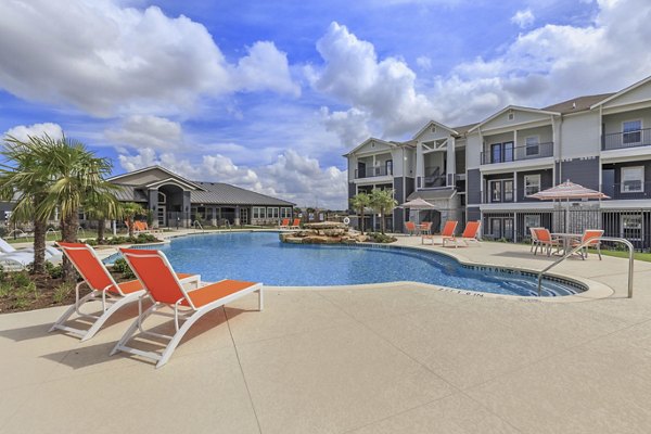 Resort-style pool at Roots at Waco Apartments with lush landscaping, perfect for relaxation and leisure activities