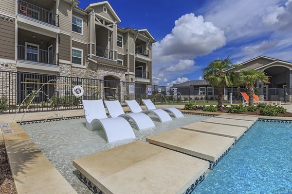Refreshing pool surrounded by lush landscaping at Roots at Waco Apartments, ideal for relaxation and leisure activities