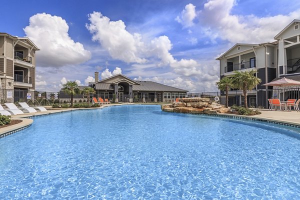 Outdoor pool with lounge chairs at Roots at Waco Apartments, perfect for relaxation and leisure activities