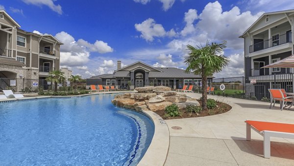 Sparkling outdoor pool at Roots at Waco Apartments featuring modern lounging areas and lush landscaping