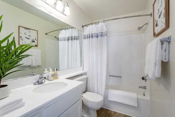 Modern bathroom with sleek fixtures and large mirror at Colony Parc Apartments