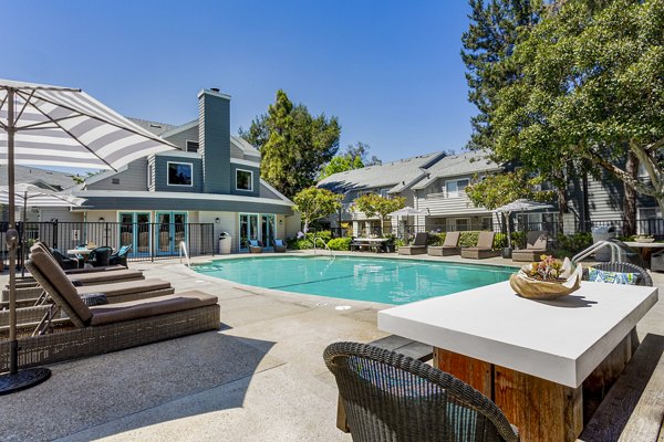 Resort-style pool at Colony Parc Apartments with lounge chairs and lush landscaping