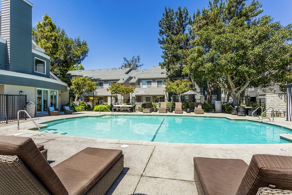 Colony Parc Apartments: Relaxing outdoor pool with lounge chairs and landscaped surroundings