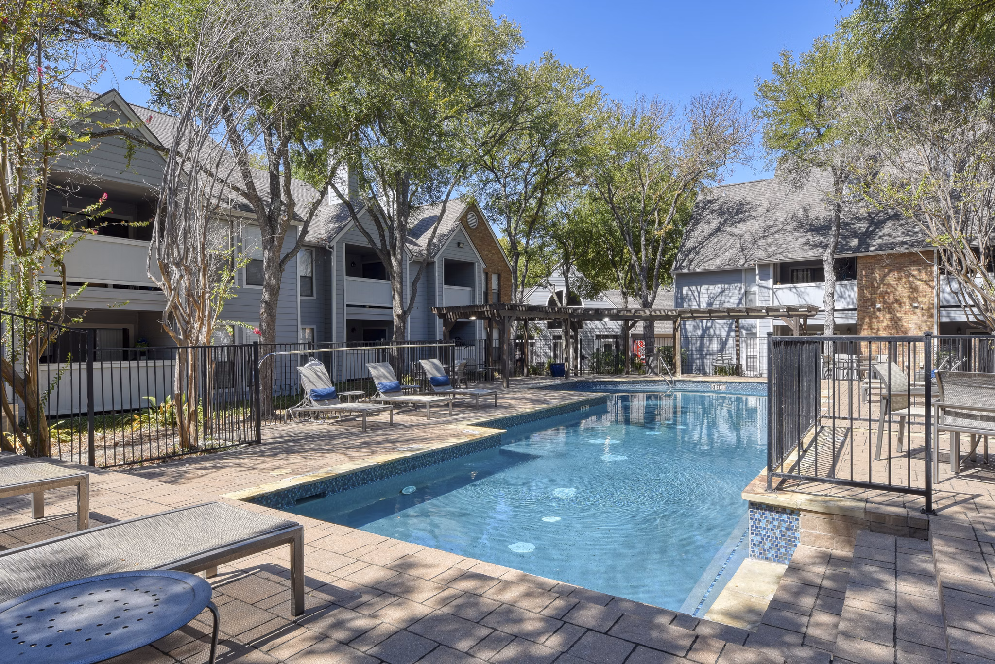 Luxurious pool at Stone Chase Apartments featuring poolside seating and lush surroundings
