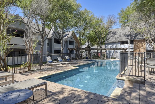 Luxurious pool at Stone Chase Apartments featuring poolside seating and lush surroundings