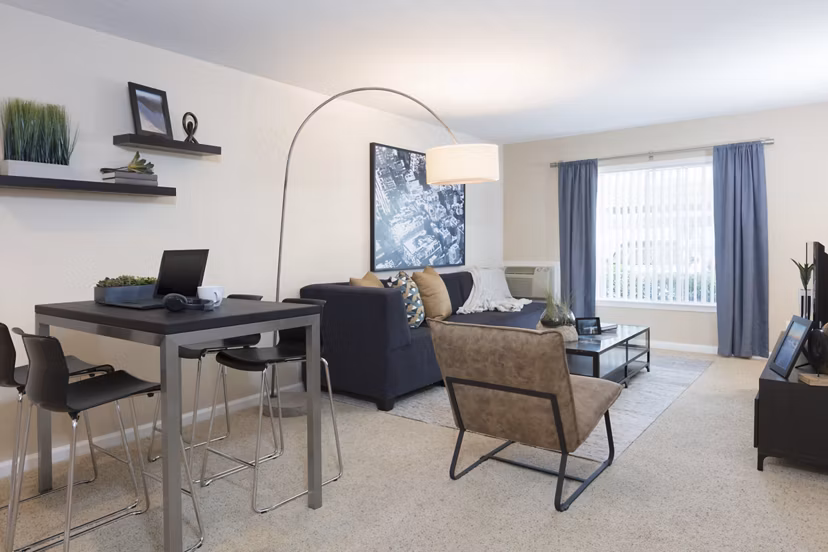Living room with contemporary decor and large windows at Central Park at Whisman Station Apartments