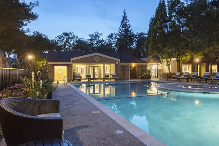 Resort-style swimming pool at Central Park at Whisman Station Apartments with luxurious lounge areas and palm trees
