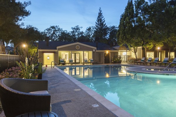 Resort-style swimming pool at Central Park at Whisman Station Apartments with luxurious lounge areas and palm trees