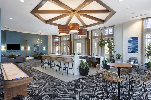 Modern clubhouse with cozy seating and large windows at Domicilio Apartments offering a welcoming ambiance for residents