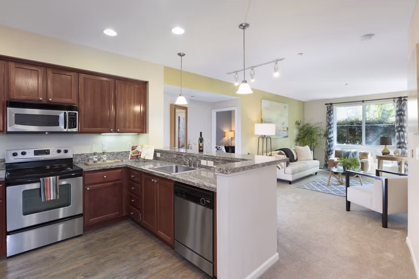 Modern kitchen with stainless steel appliances and granite countertops at Domicilio Apartments